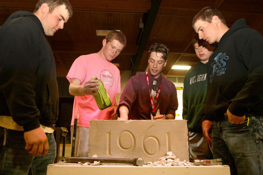 In this photo taken on Wednesday, April 23, 20134, Cascade High School's from left, senior Jake Droeszler, junior Nolan Weber, Social Studies teacher Ole Skattum, junior Danny McElmeel, and senior Jake Connolly pull out items from a time capsule from 1961 at Cascade High School in Cascade, Iowa, that was found by construction crews. The capsule was opened during a school assembly on Wednesday. (AP Photo/The Telegraph Herald, Nicole Kohl) MAGS OUT. TV OUT