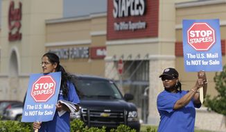 Postal worker Sophia Joseph, left, and retired postal worker Barbara Burkhalter hold signs outside a Staples store during a protest in Dallas, Thursday, April 24, 2014.  Thousands of postal workers around the nation are expected to picket outside Staples&#39; stores to protest a pilot program of postal counters in the stores that are staffed with Staples employees. (AP Photo/LM Otero)
