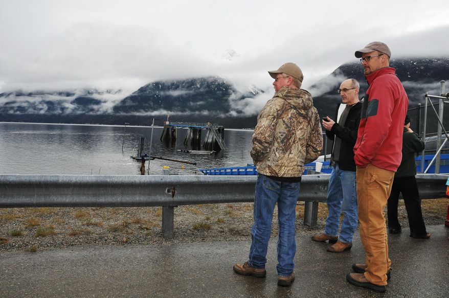 Mayor Mark Schaefer, left, borough lobbyist John Walsh, second from left, and former Skagway Ferry Terminal manager Dennis Bousson stand on the road in front of The Alaska Department of Transportation and Public Facilities (DOT&PF) Alaska Marine Highway System floating dock shown submerged underwater in Skagway, Alaska, on Thursday, April 24, 2014. The floating dock used by the state ferry system in Skagway sank overnight. The Alaska Marine Highway Service says in a Thursday release that the Skagway Ferry Terminal will be closed until further notice since the dock used by state ferries is inoperable. (AP Photo/Katherine Emmets)