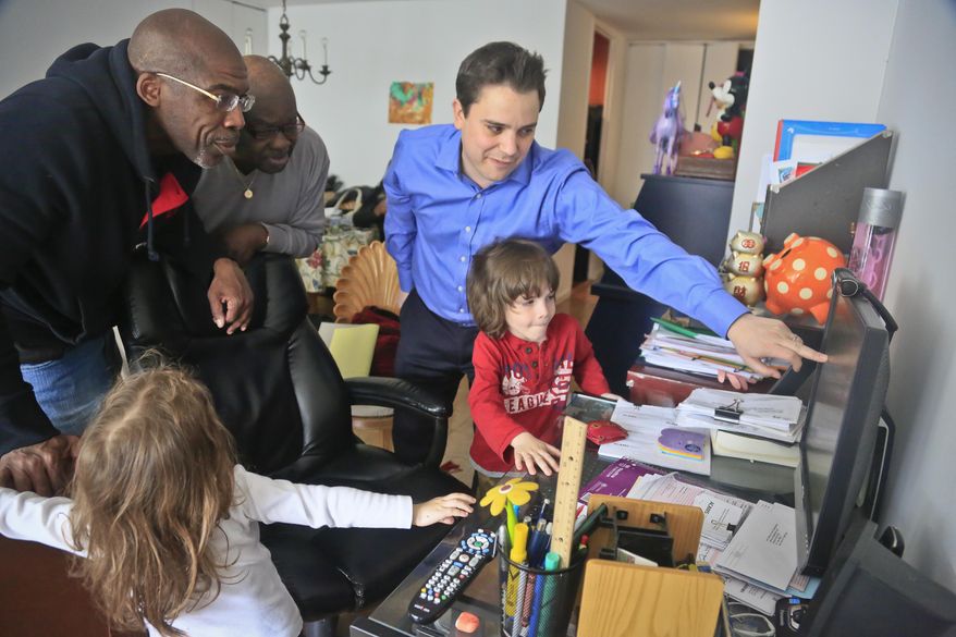 Attorney Taylor Koss, right, shows his client Jonathan Fleming, left, and his uncle Eddie Dorsey, center, an online funding website on Friday April 18, 2014 in New York. A stranger established a crowd-funding account for Fleming after he served almost 25 years behind bars for murder before his exoneration, but was released without compensation. The weeks since his release have been a mix of emotional highs and practical frustrations. “Coming back, you know, it’s been hard. ... It’s a lot to have to catch up on." (AP Photo/Bebeto Matthews)