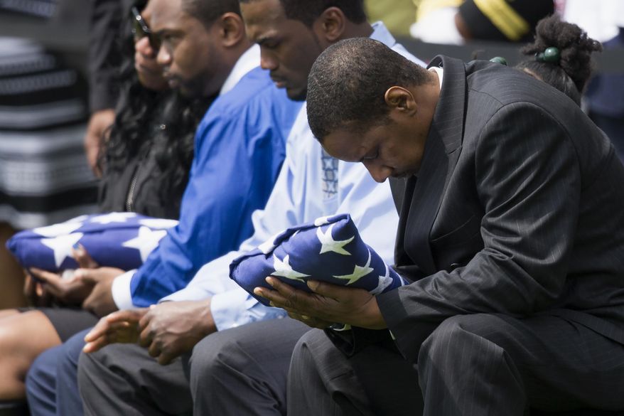 Decondi Mayo, father of U.S. Navy Petty Officer 2nd Class Mark Mayo, of Hagerstown, Md., bows his head as he holds a flag during a burial service at Arlington National Cemetery in Arlington, Va., Friday, April 25, 2014.  Mayo was killed aboard the USS Mahan at Naval Station Norfolk, Va., after he dove in front of another sailor to protect her from a civilian truck driver who had seized her gun. Mayo was awarded the Navy Marine Corps Medal, the highest non-combatant decoration for heroism by a sailor or Marine. (AP Photo/ Evan Vucci)