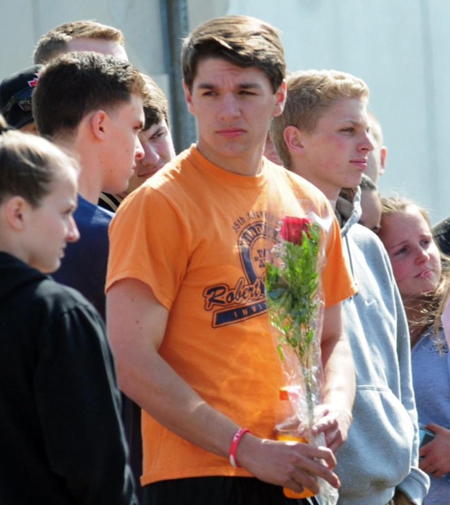 An unidentified student holds flowers at an impromptu memorial for 16-year-old stabbing victim Maren Sanchez outside Jonathan Law High School in Milford, Conn., Friday, April 25, 2014. Sanchez was stabbed to death earlier in the day during an altercation inside the school. A teenage boy is in custody, and police are investigating whether she was stabbed because she declined to be his date at the junior prom. (AP Photo/The New Haven Register, Peter Hvizdak) MANDATORY CREDIT