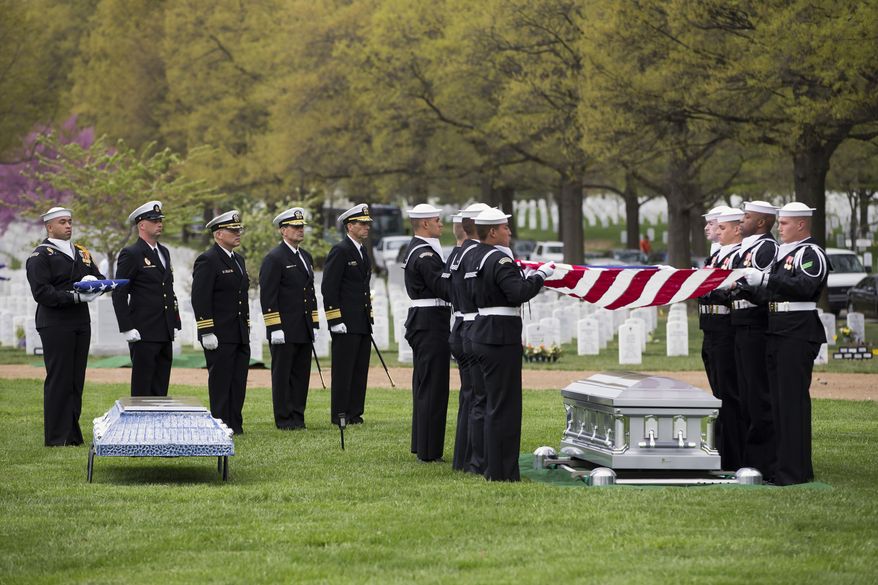 A U.S. Navy honor guard holds a flag over the casket of U.S. Navy Petty Officer 2nd Class Mark Mayo, of Hagerstown, Md., during a burial service at Arlington National Cemetery in Arlington, Va., Friday, April 25, 2014.  Mayo was killed aboard the USS Mahan at Naval Station Norfolk, Va., after he dove in front of another sailor to protect her from a civilian truck driver who had seized her gun. Mayo was awarded the Navy Marine Corps Medal, the highest non-combatant decoration for heroism by a sailor or Marine. (AP Photo/ Evan Vucci)