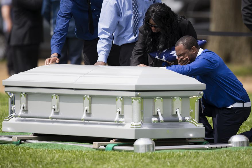 Sharon Blair, second from right, mother of U.S. Navy Petty Officer 2nd Class Mark Mayo, of Hagerstown, Md., puts her hand on her sons casket during his burial at Arlington National Cemetery in Arlington, Va., Friday, April 25, 2014. Mayo was killed aboard the USS Mahan at Naval Station Norfolk, Va., after he dove in front of another sailor to protect her from a civilian truck driver who had seized her gun. Mayo was awarded the Navy Marine Corps Medal, the highest non-combatant decoration for heroism by a sailor or Marine. (AP Photo/ Evan Vucci)