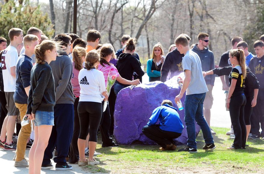 Students spray paint a rock purple outside Jonathan Law High School in Milford, Conn., Friday, April 25, 2014, in memory of 16-year-old stabbing victim Maren Sanchez. Sanchez was stabbed to death earlier in the day during an altercation inside the school. A teenage boy is in custody, and police are investigating whether she was stabbed because she declined to be his date at the junior prom. (AP Photo/The New Haven Register, Peter Hvizdak) MANDATORY CREDIT