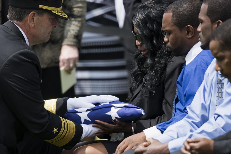 Vice Adm. William F. Moran, left, presents a flag to Sharon Blair, mother of U.S. Navy Petty Officer 2nd Class Mark Mayo, of Hagerstown, Md., during a burial service at Arlington National Cemetery in Arlington, Va., Friday, April 25, 2014.  Mayo was killed aboard the USS Mahan at Naval Station Norfolk, Va., after he dove in front of another sailor to protect her from a civilian truck driver who had seized her gun. Mayo was awarded the Navy Marine Corps Medal, the highest non-combatant decoration for heroism by a sailor or Marine. (AP Photo/ Evan Vucci)