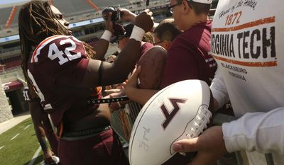 Maroon team running back Marshawn Williams (42) signs autographs for fans after Virginia Tech's annual Maroon-White spring NCAA college football game in Blacksburg, Va., Saturday, April 26 2014. (AP Photo/The Roanoke Times, Matt Gentry)