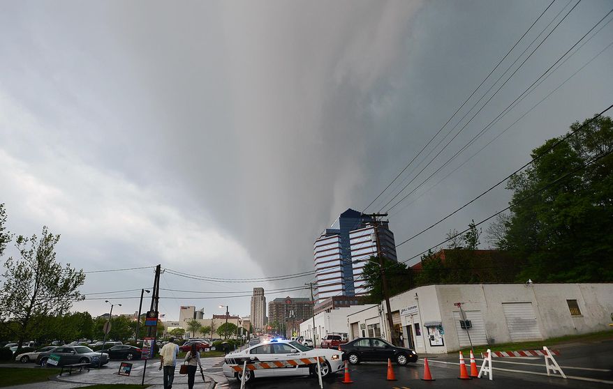 Menacing dark clouds brought rain, wind and lightning above downtown Durham North Carolina, Friday afternoon, April 25, 2014, as cold and warm fronts clashed, making a dangerous weather situation. Forecasters are predicting a significant chance of strong tornadoes this weekend across a large part of the nation's mid-section, an outbreak that could stretch from the Great Plains to the Midwest and South. (AP Photo/The Herald-Sun, Bernard Thomas)