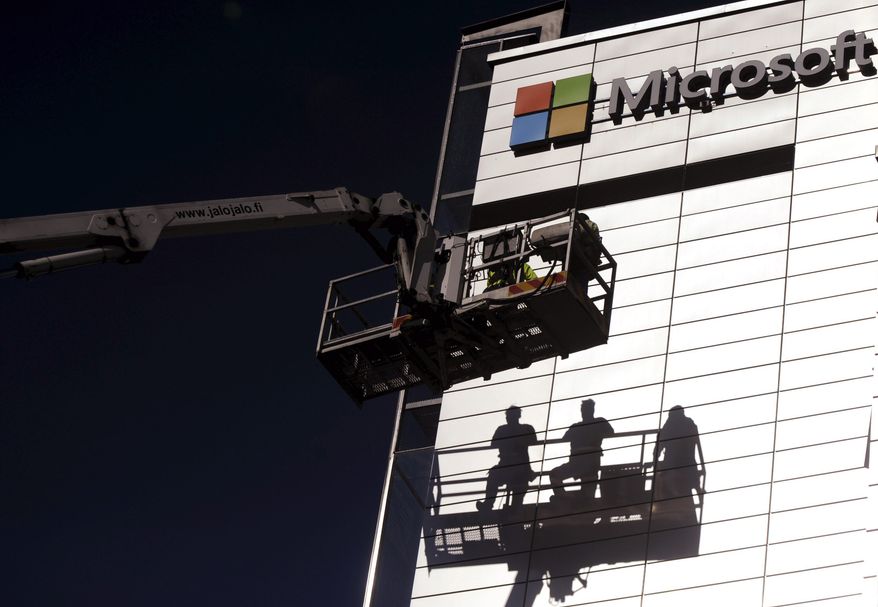 Workers install the logo of U.S. technology giant, Microsoft on the wall of Nokia's former headquarters in Espoo, Finland, Saturday, April 26, 2014. (AP Photo/Lehtikuva, Mikko Stig)