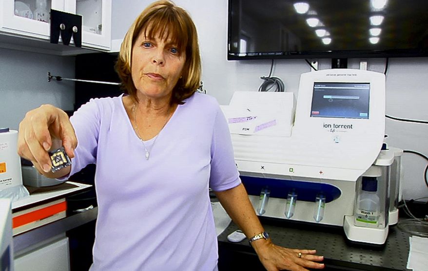 This image from video, taken March 29, 2014, shows University of Florida molecular biologist Andrea Kohn in front of a genomic sequencing machine attached to a special tilting tabletop that bobs with rough waves in this shipboard laboratory during a sail in the Gulf Stream off the coast of Florida. The lab is part of a research project to decode the genomic blueprints of fragile marine life in real time _ on board the ship where they were caught. (AP Photo/Suzette Laboy)