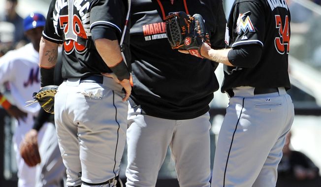 Miami Marlins pitching coach Chuck Hernandez talks with starting pitcher Tom Koehler (34) as catcher Jarrod Saltalamacchia (39) joins in after Koehler walked New York Mets Dillon Gee to load the bases in the second inning of a baseball game, Sunday, April 27, 2014, in New York. The Mets won 4-0. (AP Photo/Kathy Kmonicek)