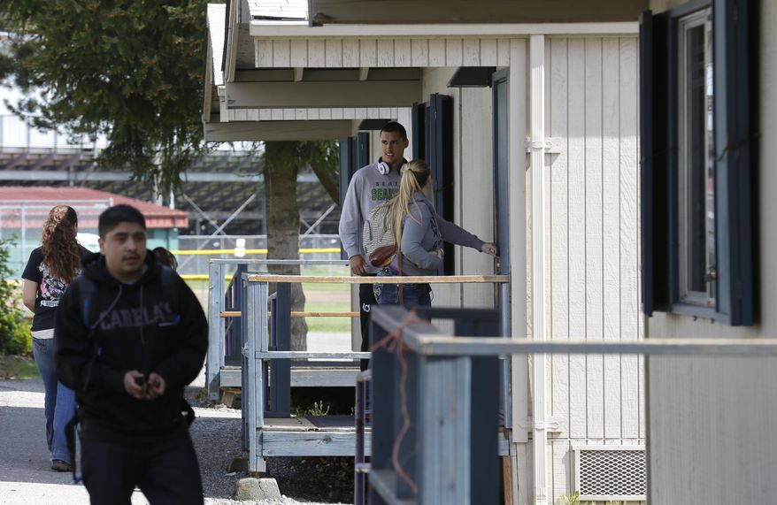 In this April 18, 2014 photo, students at North Thurston High School in Olympia, Wash., enter temporary classrooms in a cluster next to the main school building. An Associated Press analysis of Washington school enrollment data shows 136 school districts, out of 295, added students between the 2011-12 school year and the current academic year. (AP Photo/Ted S. Warren)
