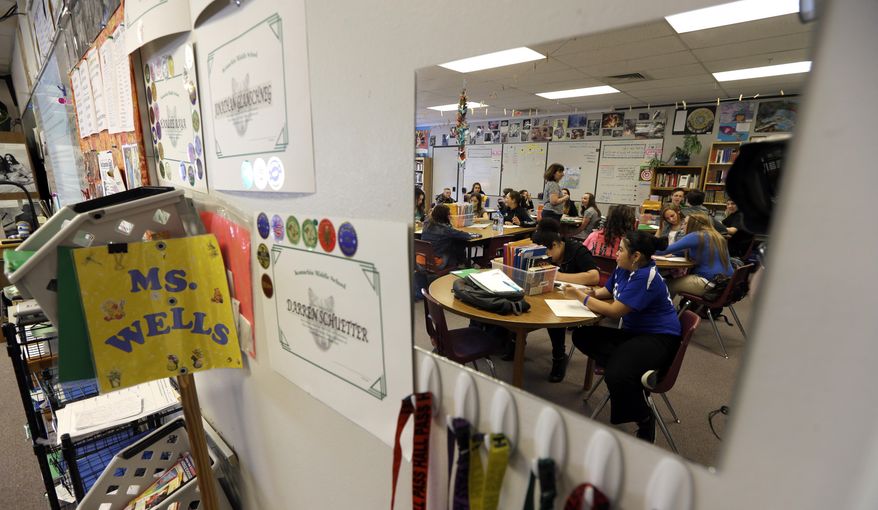 In this April 18, 2014 photo, students in Annette Wells' 7th-8th grade language arts class at Komachin Middle School in Lacey, Wash. are reflected in a mirror. Wells has switched from desks to tables due to the number of students she needs to fit in her classroom. An Associated Press analysis of Washington school enrollment data shows 136 school districts, out of 295, added students between the 2011-12 school year and the current academic year. (AP Photo/Ted S. Warren)