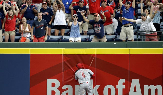 Fans celebrate as Cincinnati Reds&#x27; Billy Hamilton chases down a single by Atlanta Braves&#x27; Freddie Freeman to score the game-winning run in the 10th inning of a baseball game, Sunday, April 27, 2014, in Atlanta. The Braves won 1-0 in 10 innings. (AP Photo/David Goldman)