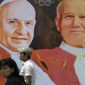 Two persons walk in front of pictures of Pope John XXIII, left, and Pope John Paul II in Guatemala City, Sunday, April 27, 2014. The canonization of Pope John Paul II and Pope John XXIII is drawing special attention in Latin America, reviving both warm memories of his frequent visits to the region and debate over his handling of sex-abuse scandals. (AP Photo/Luis Soto)