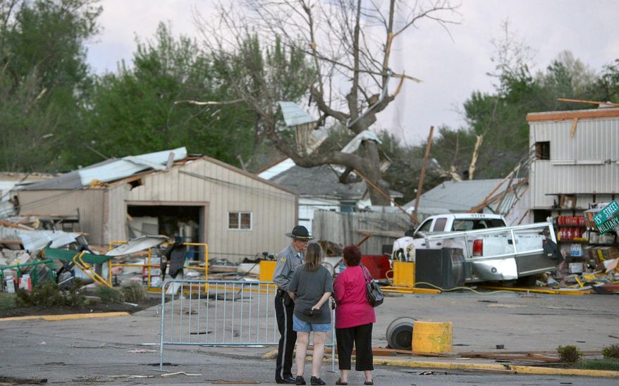 A officer talks to people at 15th and Military following Sunday's tornado in Baxter Springs, Kan., Sunday April 27, 2014. A powerful storm system rumbled through the central and southern United States on Sunday, spawning a massive tornado that carved through Little Rock's northern suburbs and another that hit Oklahoma and Kansas. (AP Photo/The Joplin Globe, Roger Nomer )