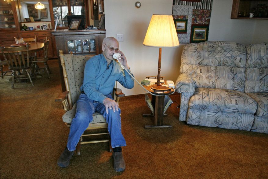 In this Wednesday, Feb. 26, 2014 photo, Gordon Levang, 95, talks on a telephone in his home in Watford City, N.D. Levang, a retired farmer, says residents have no choice but to embrace the changes that this latest oil boom has brought to their town. Oil has been found on his family's farm in all three oil booms in this region. He now lives in town and his children run the farm outside of town. He says the increase in the town's population, from 1,500 to as many as 7,000, requires him to be more patient, waiting in traffic and in lines at the grocery store. (AP Photo/Martha Irvine)