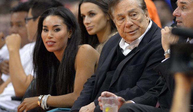FILE - In this file photo taken on Friday, Oct. 25, 2013, Los Angeles Clippers owner Donald Sterling, right, and V. Stiviano, left, watch the Clippers play the Sacramento Kings during the first half of an NBA basketball game in Los Angeles. Used car dealership chain CarMax says it is ending its sponsorship of the Clippers in the wake of racist comments attributed to Sterling. (AP Photo/Mark J. Terrill, File)