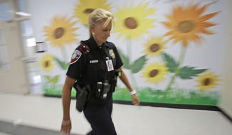 In this photo taken Thursday, Aug. 22, 2013, Dara Van Antwerp, the school resource officer at Panther Run Elementary School Pembroke Pines, Fla. walks the hallways of the school where she teaches in the Gang Resistance And Drug Education (GRADE) program in the Fort Lauderdale suburb. The armed school resource office will be permanently stationed on campus despite the decline in crime in this middle-class community. The decision comes in the wake of the Sandy Hook Elementary School shooting in Connecticut. (AP Photo/Wilfredo Lee)