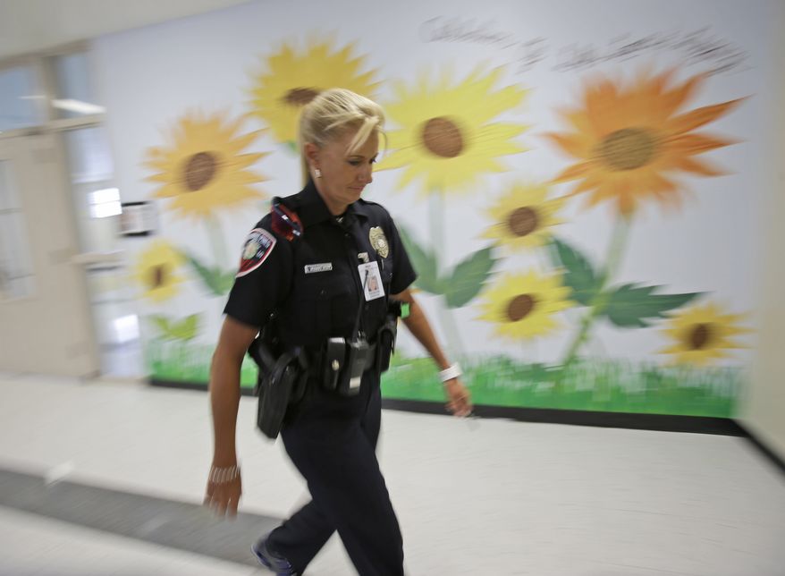 In this photo taken Thursday, Aug. 22, 2013, Dara Van Antwerp, the school resource officer at Panther Run Elementary School Pembroke Pines, Fla. walks the hallways of the school where she teaches in the Gang Resistance And Drug Education (GRADE) program in the Fort Lauderdale suburb. The armed school resource office will be permanently stationed on campus despite the decline in crime in this middle-class community. The decision comes in the wake of the Sandy Hook Elementary School shooting in Connecticut. (AP Photo/Wilfredo Lee)