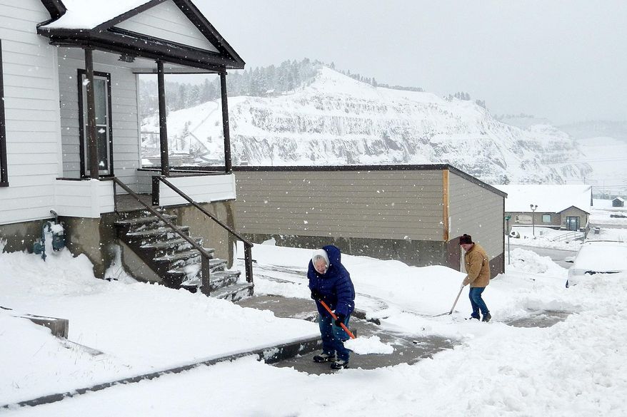 Donna Newlon, left, and her son, Lonny, clear their sidewalks Monday morning, April 28, 2014, at their home overlooking the Homestake Open Cut in Lead, S.D. A system that brought deadly weather to the central and southern U.S. over the weekend dumped heavy snow in western South Dakota late Sunday and early Monday. (AP Photo/Rapid City Journal, Tom Griffith)