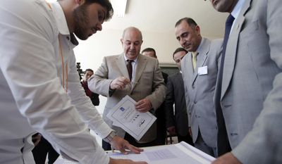 Ayad Allawi, the leader of Iraq&#39;s main Sunni-backed Iraqiya bloc and former Prime Minister, center, arrives at a polling station as his identity is checked by one of the voting watchers, for the Iraqi parliamentary election, in Amman, Jordan, Sunday, April 27, 2014. After voting Allawi expressed his views on the election, “really this is a shameful kind of elections, and I can categorize it by an election which is not worthy, not up to the standards of the Iraqi people, but this is the only way for change in Iraq, and I call upon all Iraqis to go to the ballot boxes to cast their votes to change the current situation,”Allawi said.  (AP Photo/Mohammad Hannon)