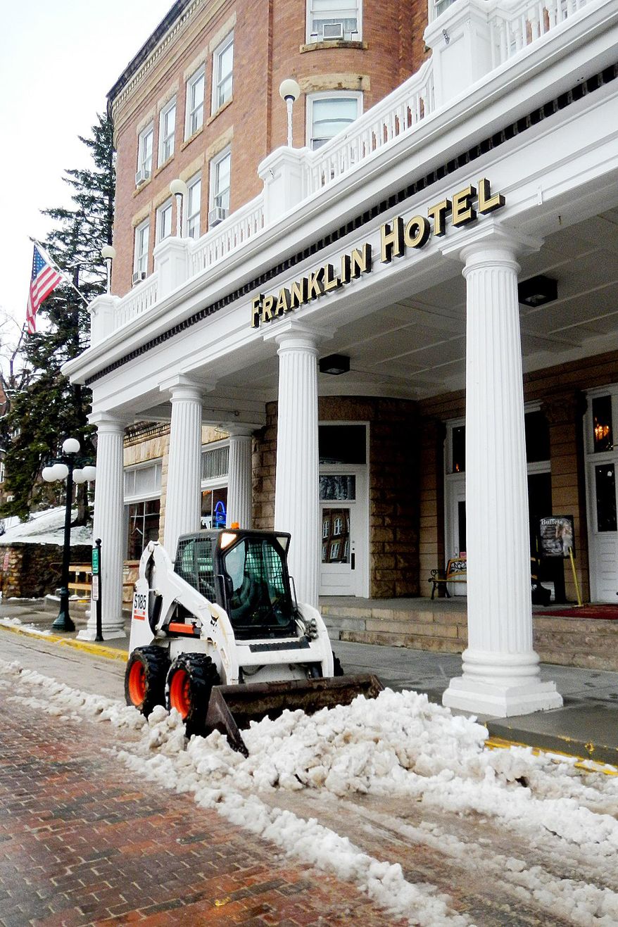 Maintenance staff at the Historic Franklin Hotel in Deadwood, S.D. clears slush from Main Street Monday morning, April 28, 2014. A system that brought deadly weather to the central and southern U.S. over the weekend dumped heavy snow in western South Dakota late Sunday and early Monday. (AP Photo/Rapid City Journal, Tom Griffith)