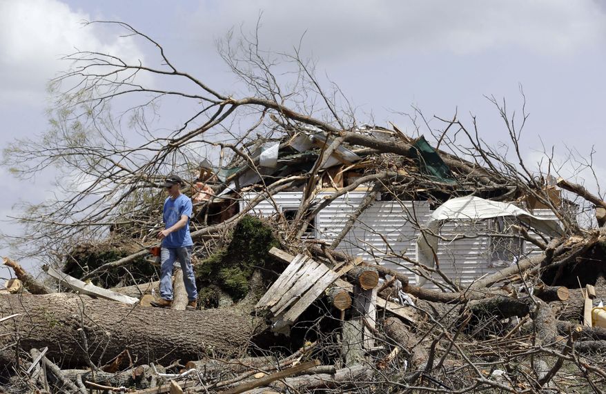 Mike Self helps to cut up trees Tuesday, April 29, 2014, that destroyed a home in Fayetteville, Tenn., when storms came through Monday. On Sunday evening, roughly 15 tornadoes carved a path of destruction in the South and the country's midsection, according to estimates from the National Oceanic and Atmospheric Administration's Storm Prediction Center. On Monday, around 50 tornadoes ravaged the South, the agency said. (AP Photo/Mark Humphrey)