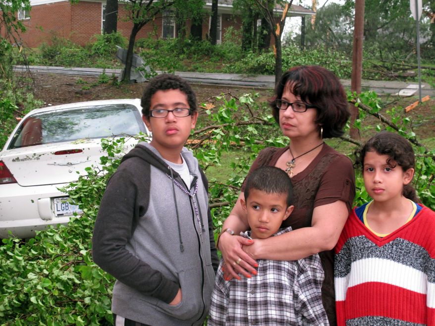 Francis Gonzalez stands with her three children as she surveys the damage caused by a tornado to her convenience store business on Monday, April 28, 2014, in Tupelo, Miss. Gonzalez and her kids ran into a cooler in the back of a convenience store, which also houses a Mexican restaurant, as a tornado approached Monday. (AP Photo/Adrian Sainz).