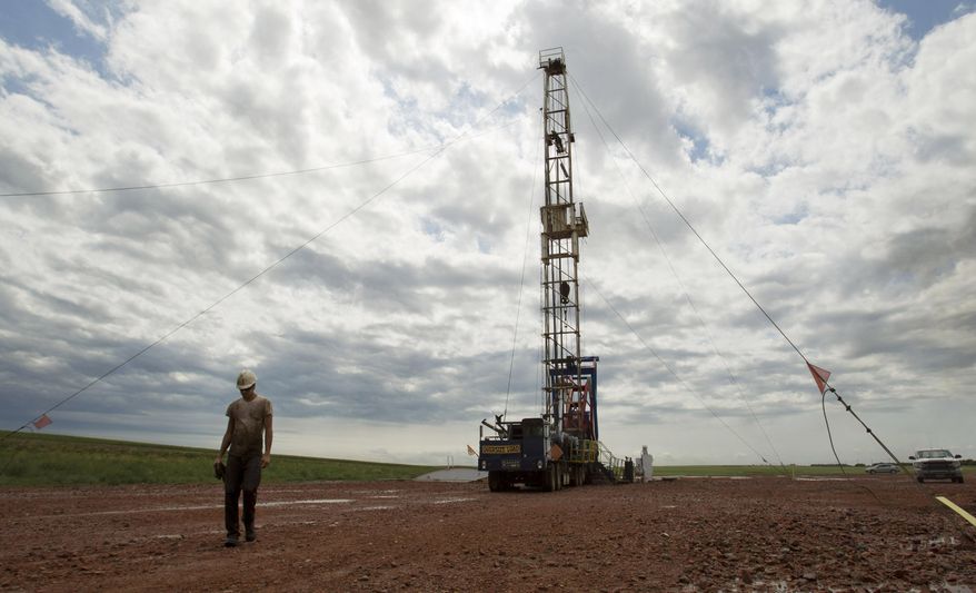 FILE - In this Tuesday, July 26, 2011 file photo, Austin Mitchell walks away from an oil derrick outside of Williston, N.D. State data show that 1 billion barrels of oil have been produced from the rich Bakken shale formation in western North Dakota and eastern Montana. Data show that North Dakota has tallied 852 million barrels of Bakken crude, and Montana has produced about 151 million barrels. (AP Photo/Gregory Bull, File)