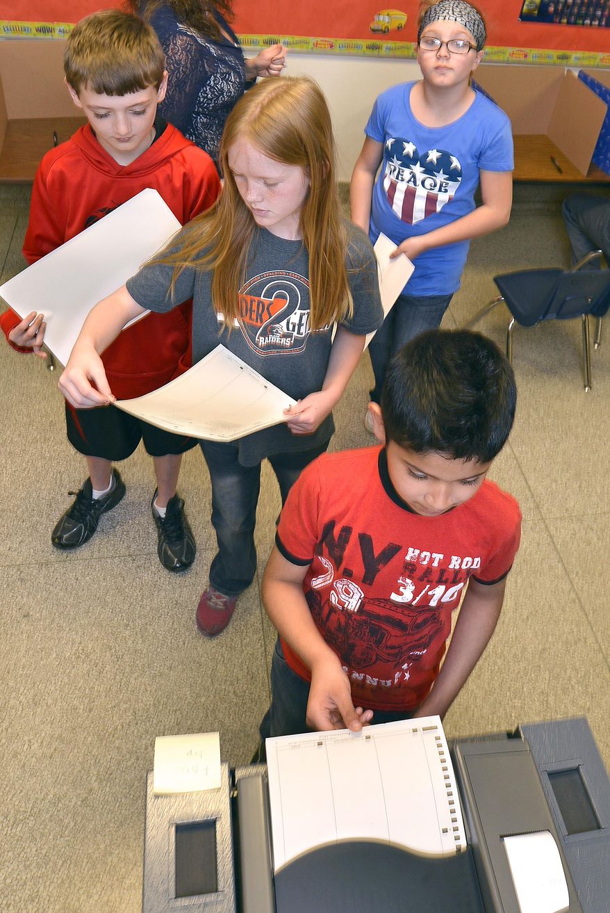 Fourth-grader Armando Gomez feeds his ballot into a voting machine during voting for a new school name Monday, April 28, 2014, at Washington Elementary School in Sioux City, Iowa. Students at Washington and Whittier schools were choosing between Discovery, Journey, Lewis and Morningside for a name for their new school building which will open in 2015. (AP Photo/The Sioux City Journal, Tim Hynds)