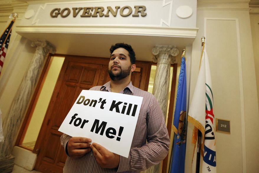 Hossein Dabiri with Oklahoma Coalition Against the Death Penalty holds a sign protesting the death penalty at the State Capitol in Oklahoma City, Tuesday April 29, 2014. Oklahoma prison officials halted the execution of an inmate after the delivery of a new three-drug combination on Tuesday failed to go as planned. (AP Photo/The Oklahoman, Steve Gooch)