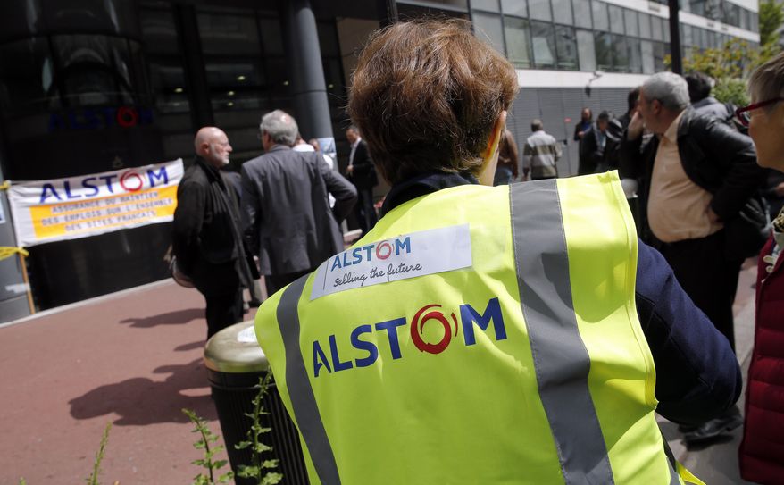 Workers gather in front of the Alstom company headquarters, the leading global maker of high-speed trains, power plants and grids, in Levallois-Perret, outside Paris, France, Wednesday, April 30, 2014. French engineering firm Alstom SA said Wednesday it was ready to accept General Electric Co.'s bid to buy its energy business, but bent to its government's order to put any deal on hold for review. (AP Photo/Christophe Ena)