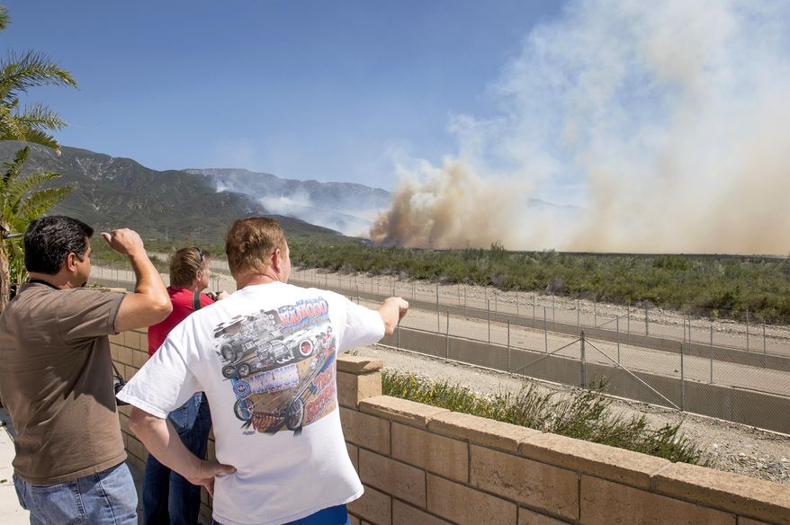 Residents watch from a backyard as smoke from the Etiwanda Fire looms behind their homes in Rancho Cucamonga, Calif., Wednesday, April 30, 2014. Dry, gusty Santa Ana winds are fanning a wildfire in the foothills of Southern California's San Bernardino Mountains. (AP Photo/San Gabriel Valley Tribune, Leo Jarzomb)