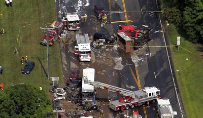 FILE - In this July 29, 2005 file photo, emergency personnel and vehicles work an accident in Avon, Conn. Lawyers for victims of the wreck, which killed four people and injured 19, argued before the state Supreme Court Wednesday, April 30, 2014, to have claims against the state Department of Transportation adjudicated before a jury. The victims have said there weren&#x27;t adequate safety precautions, like a runaway truck ramp for the steep road. The department denies the road was defective and claims government immunity. (AP Photo/Bob Child, File)