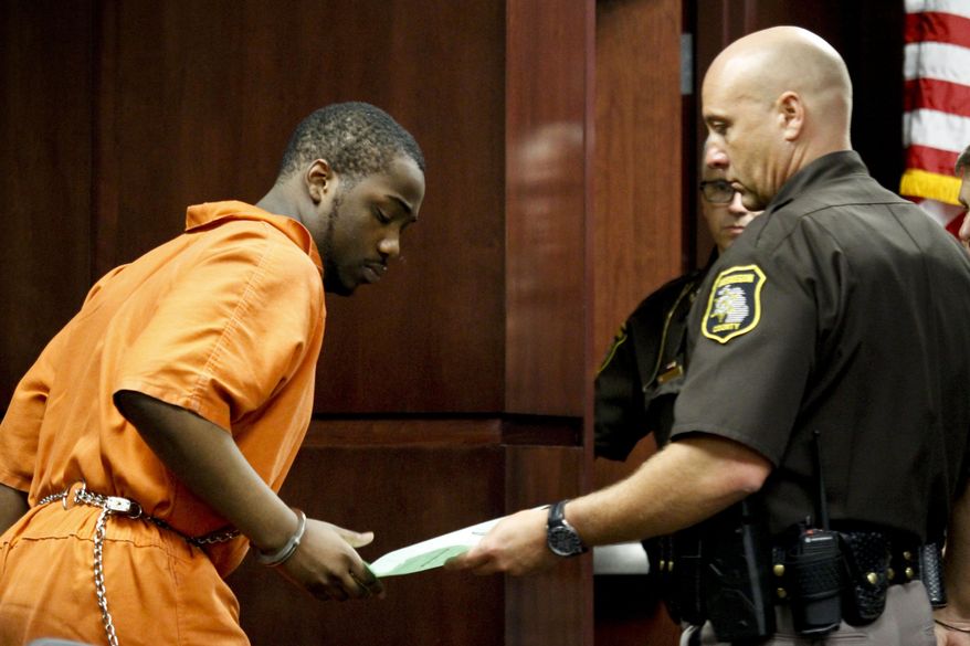 Muskegon County Sheriff's Deputy Timothy LaVigne hands over paperwork to Shundarius Lawson after his arraignment in Muskegon County District Judge Michael J. Nolan's courtroom on Wednesday, April 30, 2014 in Muskegon, Mich. Muskegon County Prosecutor D.J. Hilson says Lawson, 20, was in a sport utility vehicle from which shots were fired that killed 17-year-old Marquis Gresham on April 23. According to Hilson, the investigation is continuing, and more charges against others are possible. Gresham was a junior and a starting center on the Muskegon Heights Public School Academy team that advanced to the state semifinals. (AP Photo/The Muskegon Chronicle, Madelyn Hastings) ALL LOCAL TV OUT; LOCAL TV INTERNET OUT