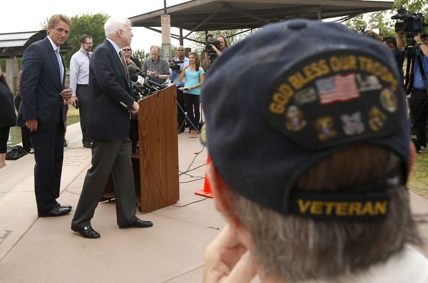 **FILE** With Vietnam military veteran Chuck Tharp (right) listening in, Arizona Republican Sens. John McCain (second from left) and Sen. Jeff Flake (left) finish up a news conference to discuss recent reports that dozens of VA hospital patients in Arizona may have died while awaiting medical care in the Phoenix VA Health Care System, adjacent to the VA Hospital on April 18, 2014, in Phoenix. Last week's disclosures by current and former Department of Veterans Affairs employees is leading to investigations by the House Committee on Veterans Affairs and the Inspector General for the VA are looking into not only the deaths, but allegations of falsified record keeping and medical reporting. (Associated Press)
