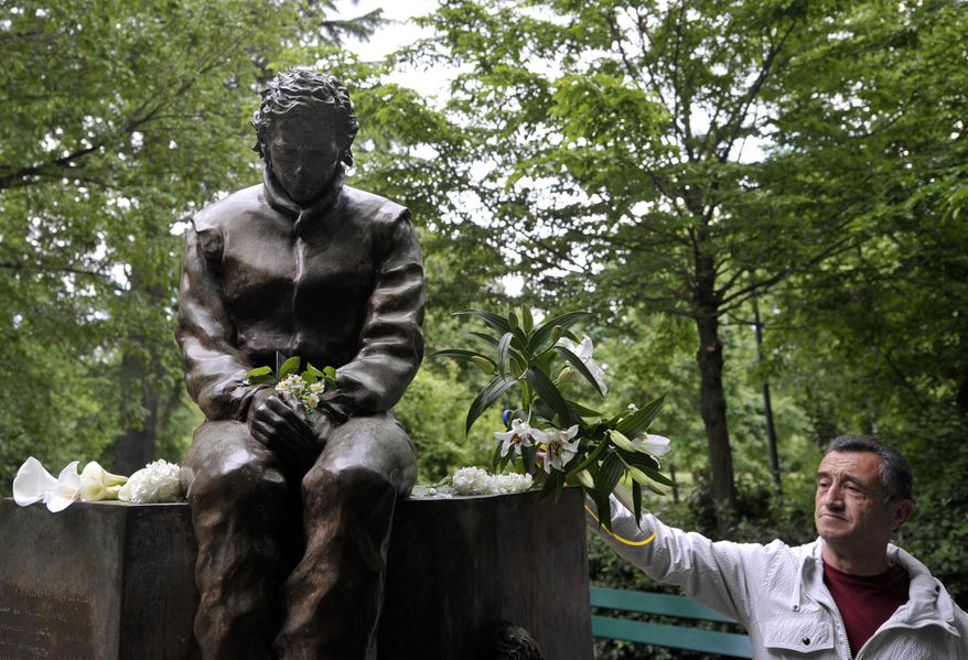 A man lays flowers next to a statue of Ayrton Senna, in a park close to the Imola track, Italy, Wednesday, April 30, 2014. It is a testament to Ayrton Senna's lasting impact on Formula One that the 20th anniversary of his death will be observed this week with five days of commemorations at the Imola track where he had his fatal accident. Current and past F1 drivers, mechanics, racing officials and fans will pay their respects to Senna and Austrian driver Roland Ratzenberger, who also died at the 1994 San Marino Grand Prix. (AP Photo/Marco Vasini)