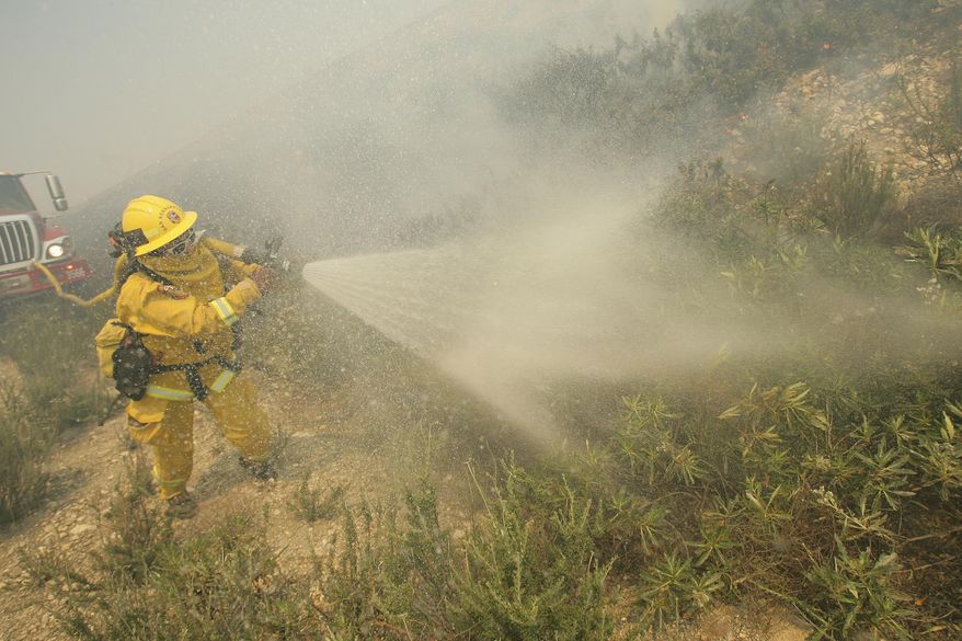 A firefighter sprays down brush as he battles a fire burning in Day Creek near the Etiwanda Preserve in Rancho Cucamonga, Calif., on Wednesday, April 30, 2014. Fire officials say winds gusting to 60 mph are pushing the flames through the foothills of the San Bernardino Mountains east of Los Angeles, although no homes are in immediate danger. Several neighborhoods and at least seven schools in Rancho Cucamonga have been evacuated. There’s no word on what sparked the blaze but it comes in the midst of a heat wave that’s created extreme fire danger. (AP Photo/The Press-Enterprise, Stan Lim) MAGS OUT; MANDATORY CREDIT