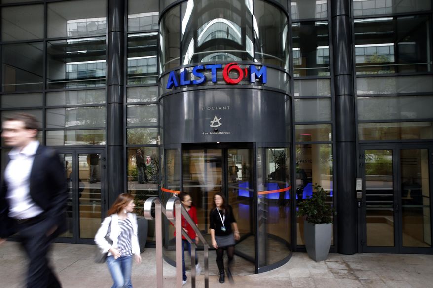 Workers leave the Alstom company headquarters, the leading global maker of high-speed trains, power plants and grids, in Levallois-Perret, outside Paris, France, Wednesday, April 30, 2014. French engineering firm Alstom SA said Wednesday it was ready to accept General Electric Co.'s bid to buy its energy business, but bent to its government's order to put any deal on hold for review. (AP Photo/Christophe Ena)