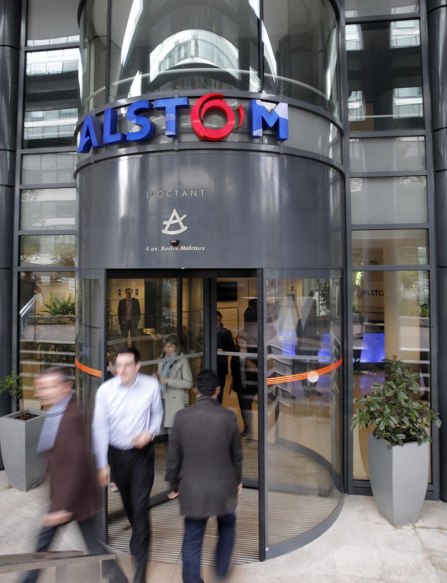 Workers leave the Alstom company headquarters, the leading global maker of high-speed trains, power plants and grids, in Levallois-Perret, outside Paris, France, Wednesday, April 30, 2014. French engineering firm Alstom SA said Wednesday it was ready to accept General Electric Co.'s bid to buy its energy business, but bent to its government's order to put any deal on hold for review. (AP Photo/Christophe Ena)