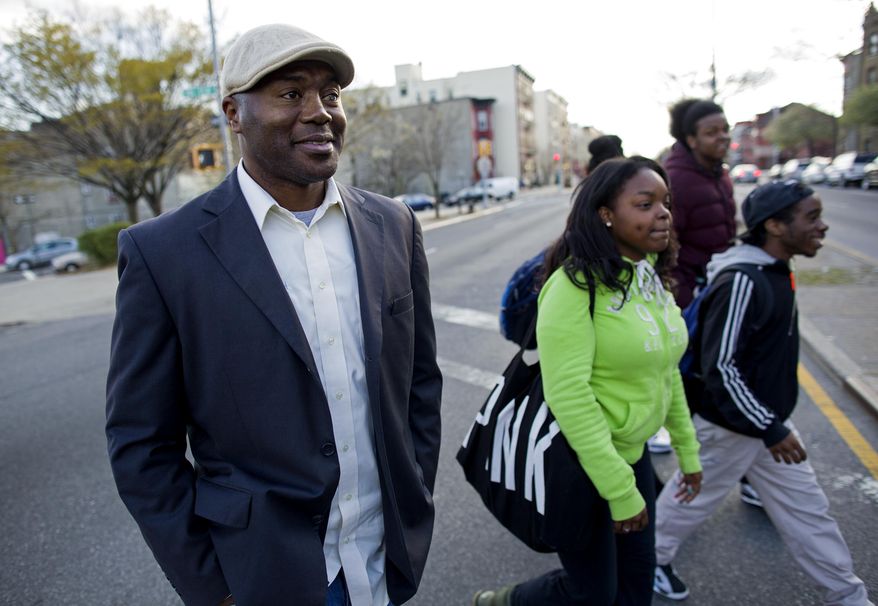 In a photograph taken Wednesday, April 23, 2014, Dr. Kai Smith, former gang member and now founder and Executive Director of GRAAFICS (Gang Diversion, reentry and Absent Father Intervention Center), walks with GRAAFICS students Tyasia Blair, 16, of East New York, Devon Collins, 16, of East New York, and Jamal Williams, 18 (background right) in the Brownsville neighborhood of Brooklyn, N.Y. They along with other students at the nearby Brooklyn Collegiate High School enter the GRAAFICS program if they have been part of a "crew," and work to stay focused on getting on with their educations and lives without being part of a neighborhood crew. (AP Photo/Craig Ruttle)