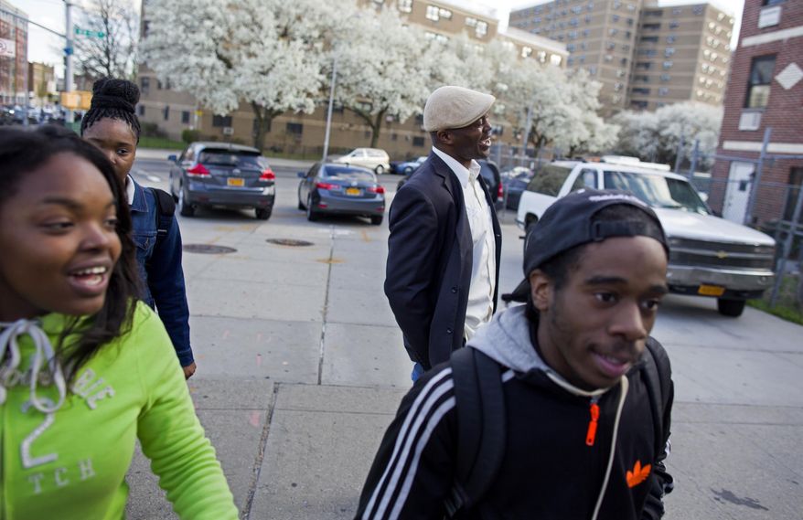 In a photograph taken Wednesday, April 23, 2014, Dr. Kai Smith, background center right, former gang member and now founder and Executive Director of GRAAFICS (Gang Diversion, reentry and Absent Father Intervention Center), laughs as he walks with GRAAFICS students (from left) Tyasia Blair, 16, of East New York, Keeozel Saul, 16, and Devon Collins, 16, of East New York, in the Brownsville neighborhood of Brooklyn, N.Y. They along with other students at the nearby Brooklyn Collegiate High School enter the GRAAFICS program if they have been part of a "crew," and work to stay focused on getting on with their educations and lives without being part of a neighborhood crew. (AP Photo/Craig Ruttle)