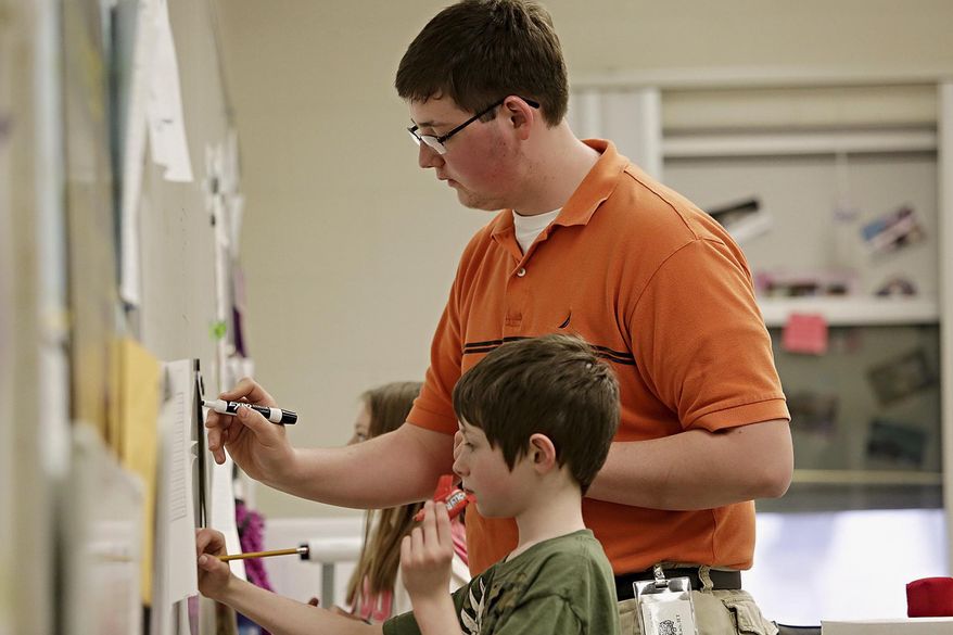 ADVANCE FOR USE SUNDAY, MAY 4 AND THEREAFTER - In this April 10, 2014 photo, Jimmy Brinkmeyer, front, 10, is helped with a division problem by Daniel Lacy at Stevens Intermediate School in Wilmington, Ill. Lacy is a senior at Wilmington High School and is one of the eight local 2014 Golden Apple Scholars, a program formed in 1989 that fosters young educators and provides tuition assistance for college. (AP Photo/The Herald-News, Rob Winner) MANDATORY CREDIT