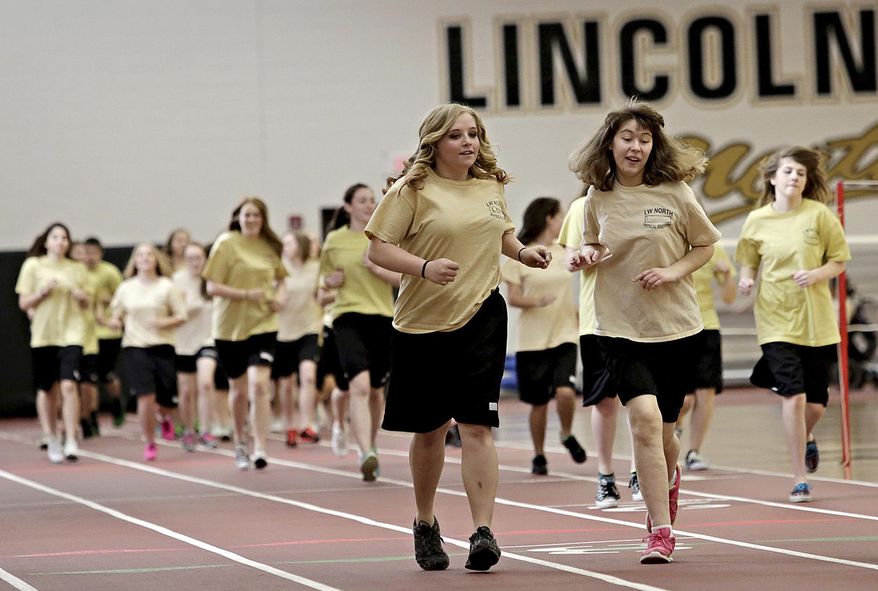 ADVANCE FOR USE SUNDAY, MAY 4 AND THEREAFTER - In this April 11, 2014 photo, adaptive physical education leader Katelyn Lowery, 18, left, and Elizabeth Limanowski, 16, run together on the track inside the field house at Lincoln-Way North High School in Frankfort, Ill. Lowery is one of the eight local 2014 Golden Apple Scholars, a program that fosters young educators and provides tuition assistance for college. (AP Photo/The Herald-News, Rob Winner) MANDATORY CREDIT