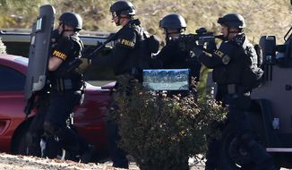 FILE - This Jan. 30, 2013 file photo shows members of the Phoenix Police Department SWAT team preparing to enter the home of a suspected gunman who opened fire at a Phoenix office building, wounding three people, one of them critically, in Phoenix. Phoenix is reviewing five years of data on shootings by police officers in hopes of learning what can be done better and avoiding potential legal trouble. Police Chief Daniel Garcia says the Police Department will study factors and situations that lead to violent confrontations.  (AP Photo/Ross D. Franklin, file)