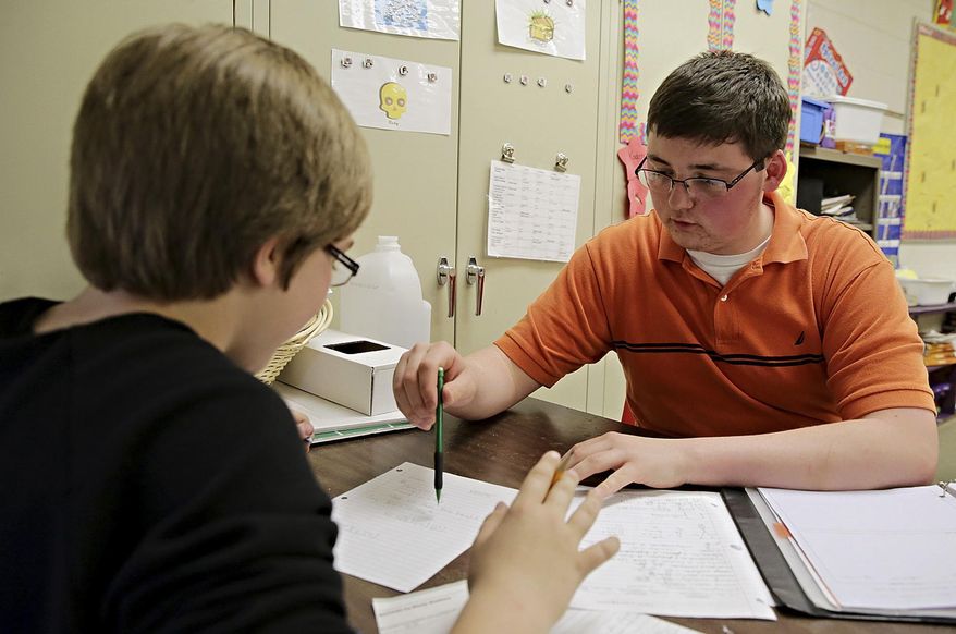 ADVANCE FOR USE SUNDAY, MAY 4 AND THEREAFTER - In this April 10, 2014 photo, Brad Stacy, left,11, is helped with a mathematical equation by Daniel Lacy at Stevens Intermediate School in Wilmington, Ill. Lacy is a senior at Wilmington High School and is one of the eight local 2014 Golden Apple Scholars, a program formed to provide tuition assistance during undergraduate studies to prepare students to teach children in challenging school environments. (AP Photo/The Herald-News, Rob Winner) MANDATORY CREDIT