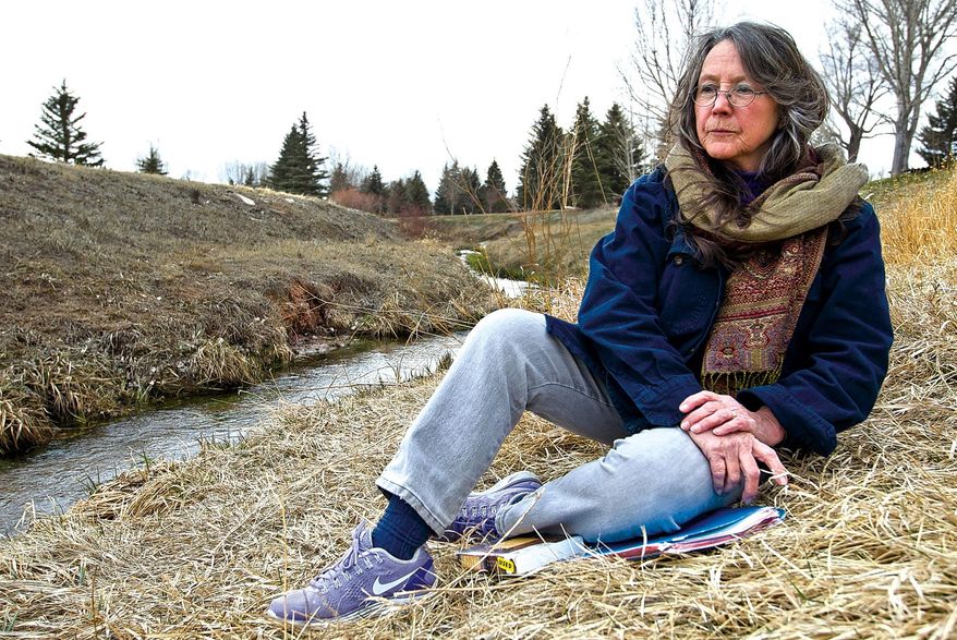 In this Thursday, April 10, 2014 photo, Sally Palmer, a University of Wyoming department of religious studies adjunct assistant lecturer, sits near Spring Creek in LaPrele Park in Laramie, Wyo. with a stack of student papers to be graded. She teaches classes about life beyond death, how religion and science can coexist, and how religions compare to one another. (AP Photo/Laramie Boomerang, Jeremy Martin)