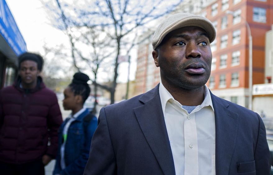 In a photograph taken Wednesday, April 23, 2014, Dr. Kai Smith, former gang member and now founder and Executive Director of GRAAFICS (Gang Diversion, reentry and Absent Father Intervention Center), stands on a corner in the Brownsville neighborhood of Brooklyn, N.Y. Students at the nearby Brooklyn Collegiate High School enter the GRAAFICS program if they have been part of a "crew," and work to stay focused on getting on with their educations and lives without being part of a neighborhood crew. Background left are Jamal Williams, 18, and Keeozel Saul, 16, who are in the program. (AP Photo/Craig Ruttle)