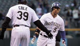 Colorado Rockies third base coach Stu Cole (39) congratulates Rockies&#39; Carlos Gonzalez (5) after Gonzalez&#39;s home run in the first inning of a baseball game against the New York Mets in Denver, Thursday, May 1, 2014.(AP Photo/Joe Mahoney)
